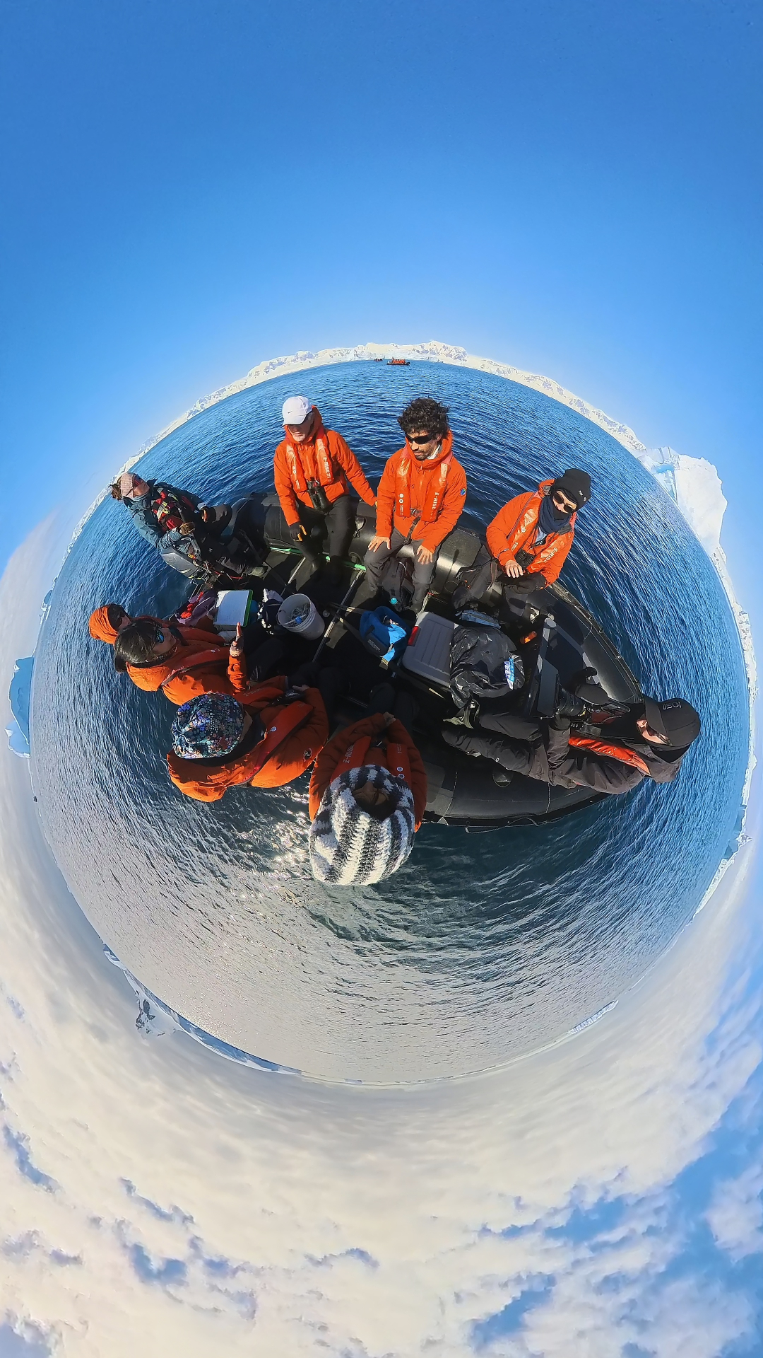 Antarctic expedition ship with travelers in a Zodiac collecting water samples